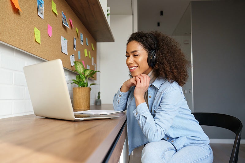 The image shows a person participating in an online interaction or remote work session while seated at a desk